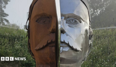 Sculpture showing a face in two halves, one side is shiny silver metal, the other is rust
