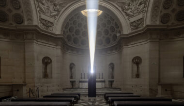 a beam of white light carves through paris' historical chapel