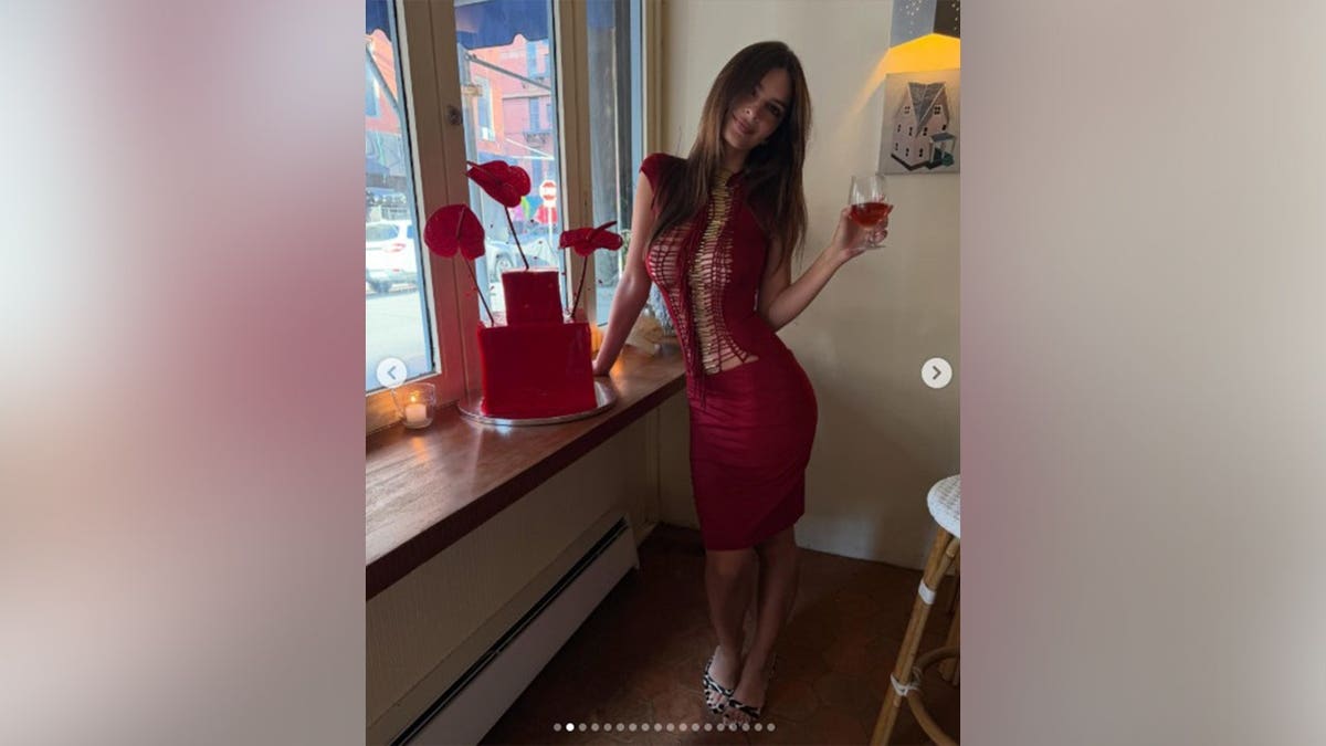 Emily Ratajkowski in a red dress next to her birthday cake in an Instagram picture.