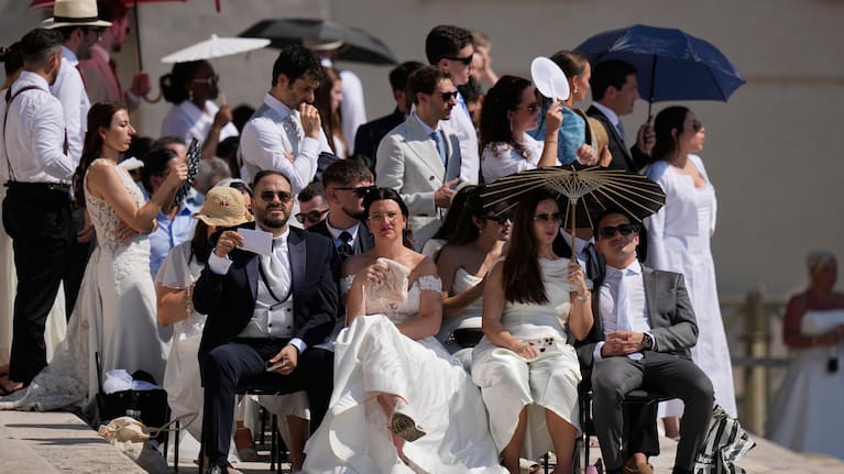 Faithful shelter for the hot sun as they wait for Pope Leo's XIV weekly general audience in St. Peter's Square at The Vatican.
