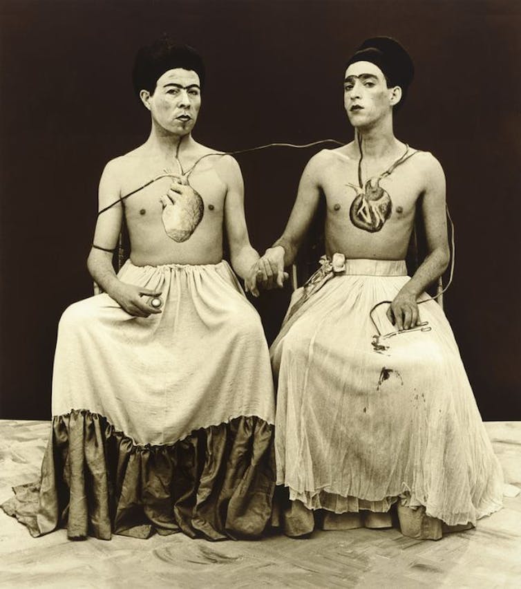 Recreation of a Kahlo painting, two people sat hand in hand.