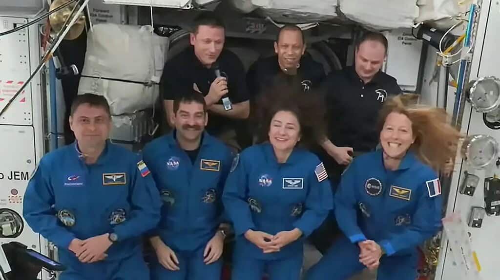 Group of NASA astronauts inside spacecraft, smiling and posing for photo.
