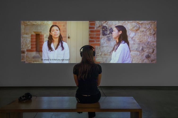 A woman watches a two-channel video.