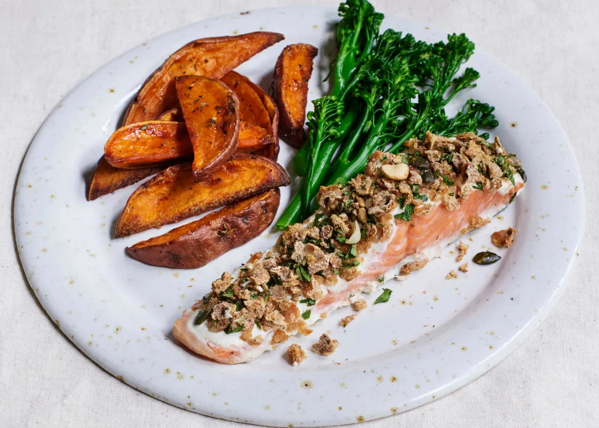A plate of salmon, broccoli and sweet potato wedges