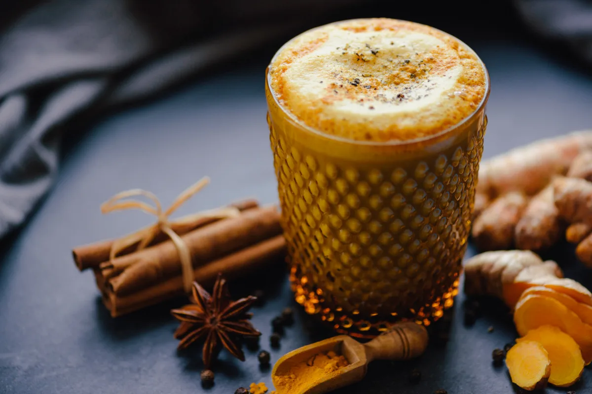 Turmeric latte or golden latte made of turmeric and vegan organic almond milk topped with pepper and powdered turmeric