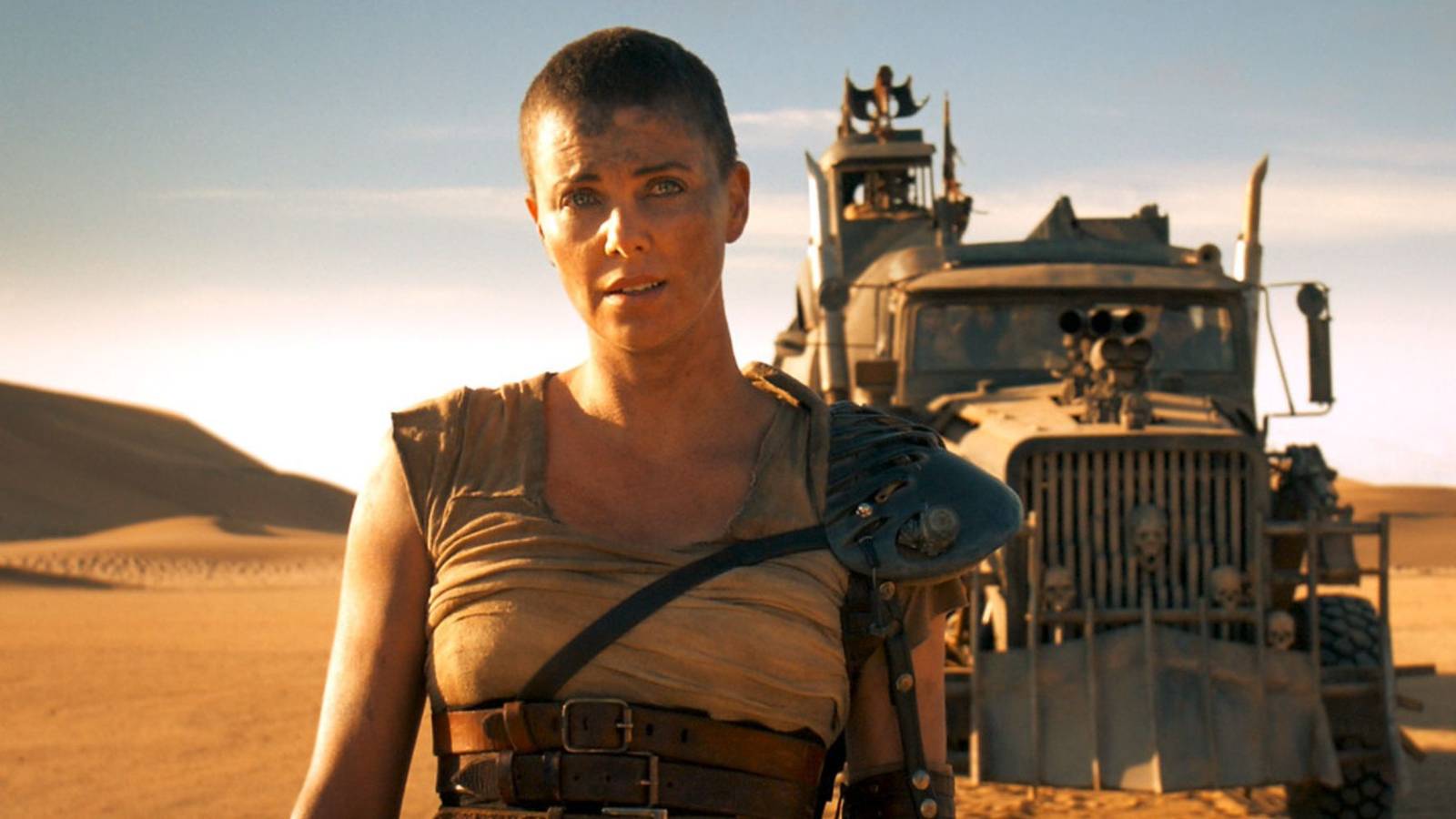 Furiosa stands in front of a dilapidated truck in the desert in Mad Max: Fury Road.