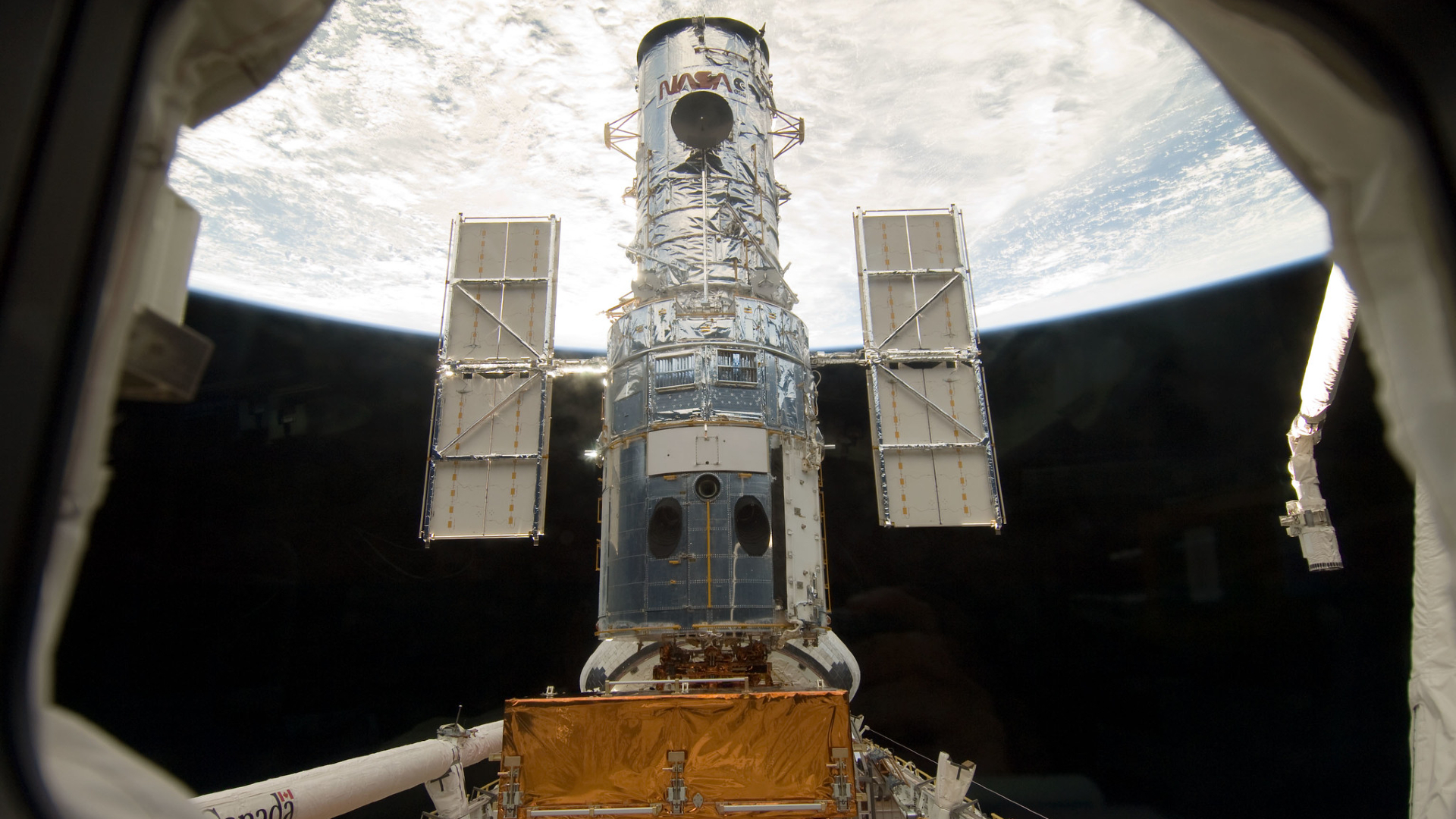 A silver-wrapped telescope in space above Earth.