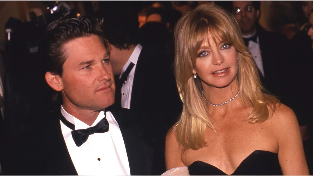Kurt Russell in tuxedo and Goldie Hawn in black dress posing in New York City