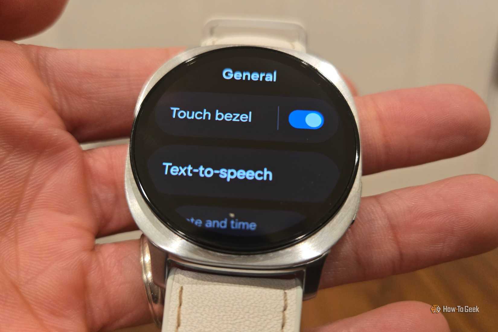 Hand holding a Samsung Galaxy Watch 8 showing the Touch Bezel setting