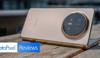 A gold-colored smartphone with a large circular camera module is propped up on a wooden surface. The “PetaPixel Reviews” logo appears in the bottom left corner of the image.