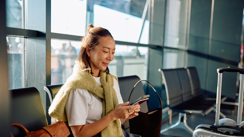 A woman using a gadget while waiting at an airport.
