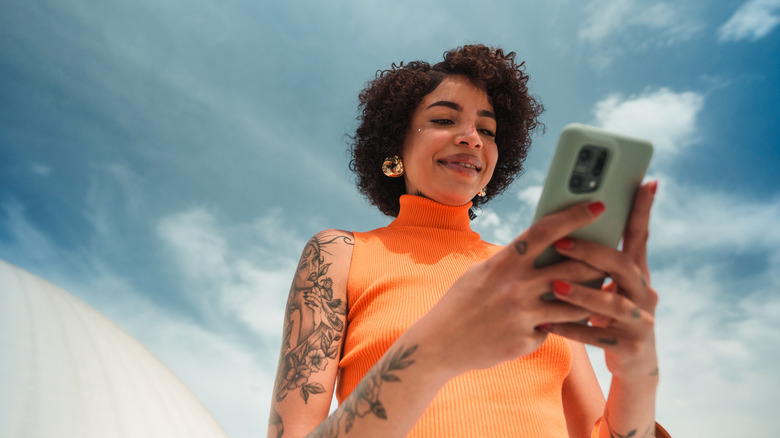 A person using a smartphone under direct sunlight outdoors
