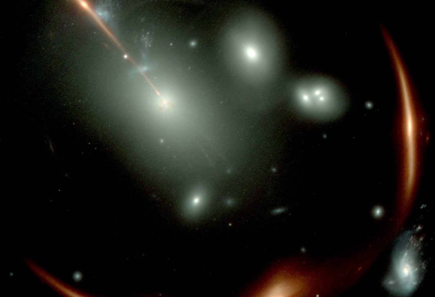 A JWST image of the highly distorted red galaxy MRG-M0138 seen through a foreground cluster of galaxies (white sources). Via the phenomenon of gravitational lensing, the same background galaxy is multiply imaged four times. Courtesy: NASA/JWST