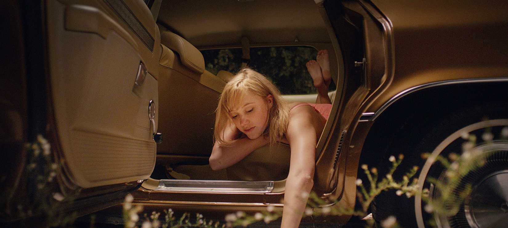 Maika Monroe leaning out of a car in It Follows