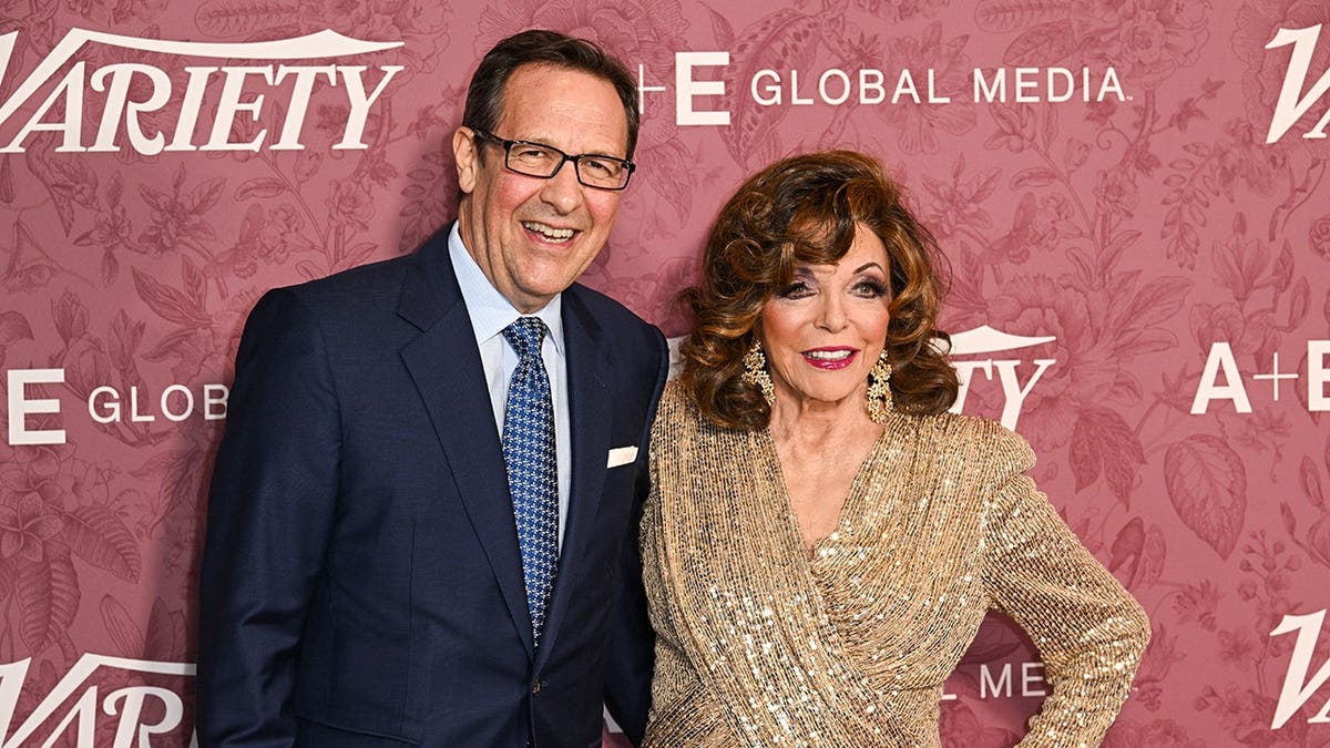 Percy Gibson and Joan Collins standing together at an event in London