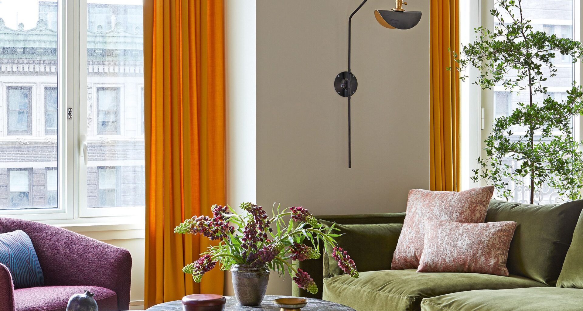 Living room with olive green chaise longue sofa, grey marble coffee tables, purple armchair and orange curtains
