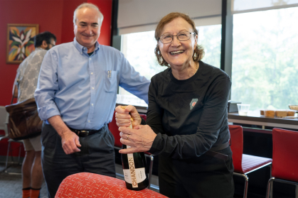 Eva Andrei during a department celebration holding a bottle of champagne 