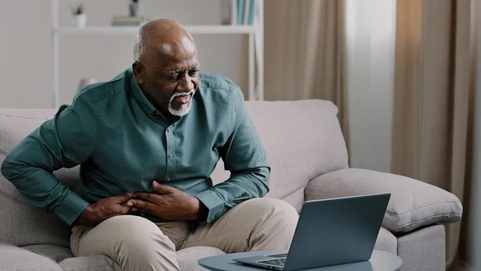 Man holding his stomach at a desk, one of the physical symptoms of anxiety people often misread