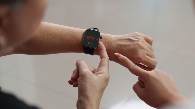 Two people pointing to a smartwatch screen