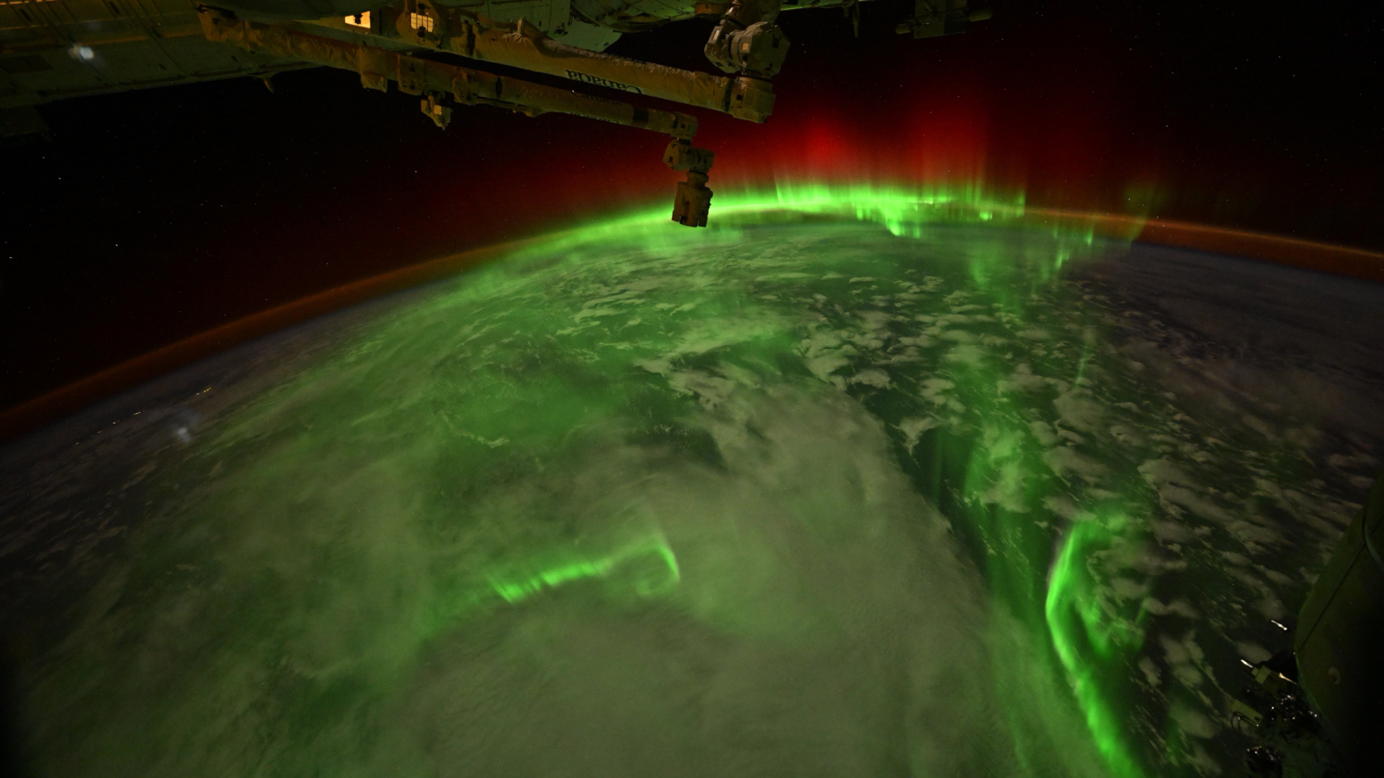 Bright green and red auroras are seen over Earth from space.