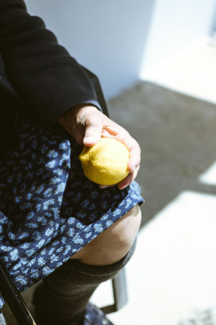 Elderly person holding lemon while sitting, highlighting dementia care