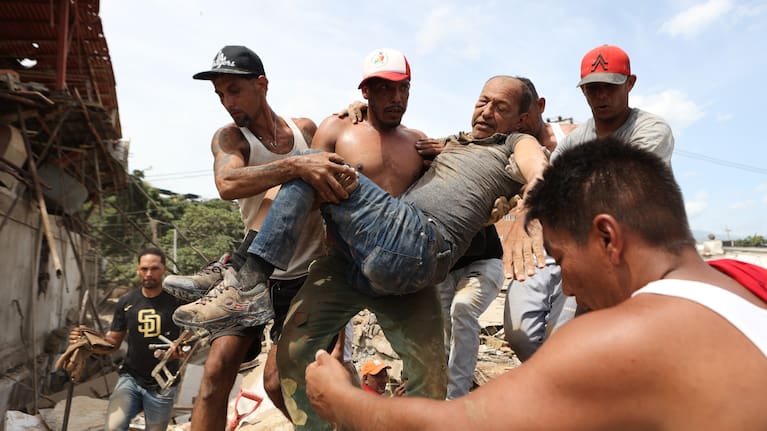 Neighbors carry a man rescued from the rubble of a collapsed building the day after earthquakes struck La Guaira, Venezuela.