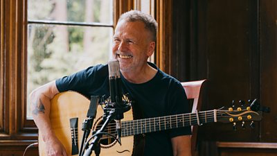 Martin Simpson playing the guitar with a mic in front of him