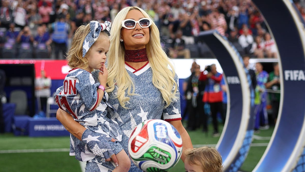 Paris Hilton standing with children at Los Angeles Stadium before FIFA World Cup match.
