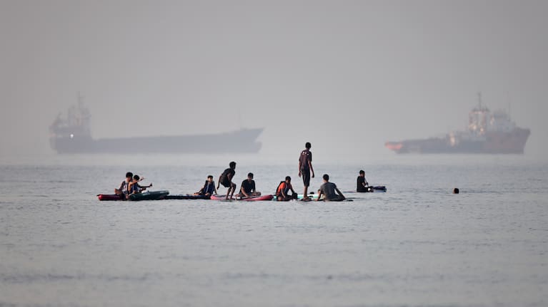 People gather on paddleboards in shallow water as cargo and service vessels are anchored in the Strait of Hormuz off Bandar Abbas, Iran, Monday, June 1, 2026.