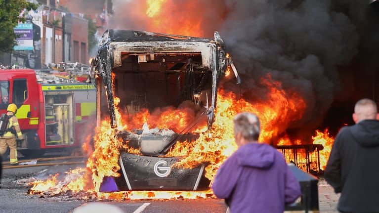 People watch as firemen arrive to put out vehicle that was set alight during a protest in East Belfast following a stabbing incident in Belfast.