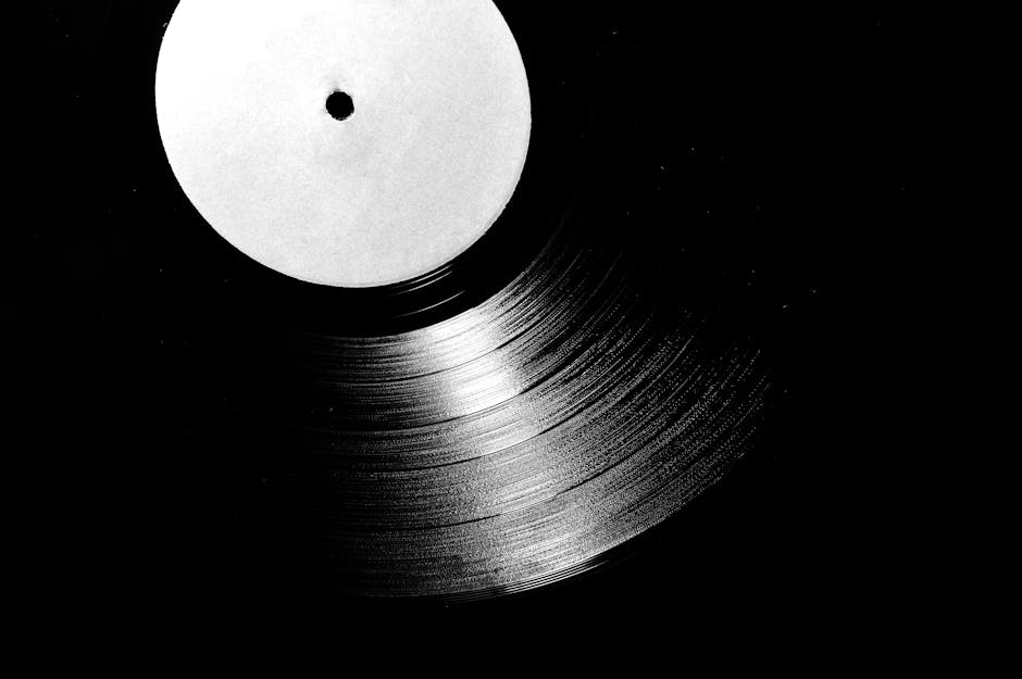 A close-up of a vintage vinyl record in black and white, emphasizing its grooves.