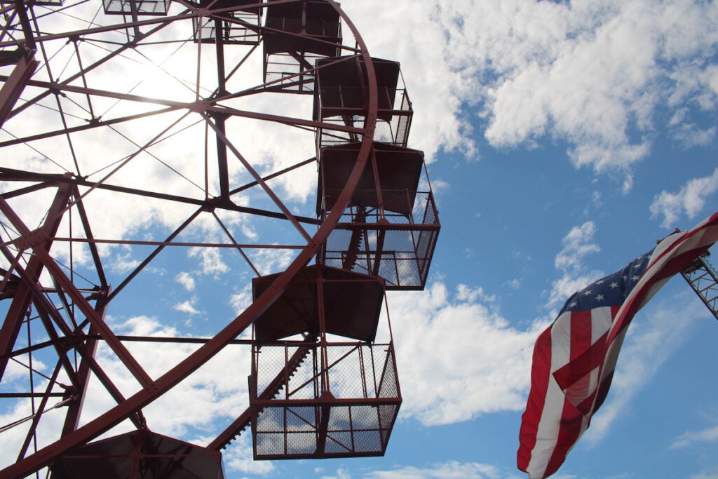 A ferris wheel is shown with an American flag next to it