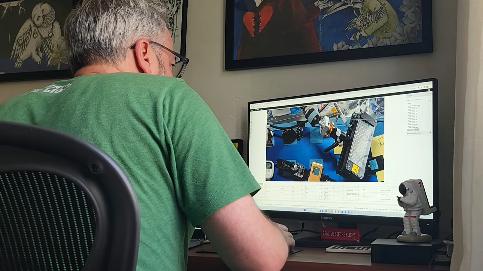 a light-skinned man in a green T-shirt works at a computer monitori
