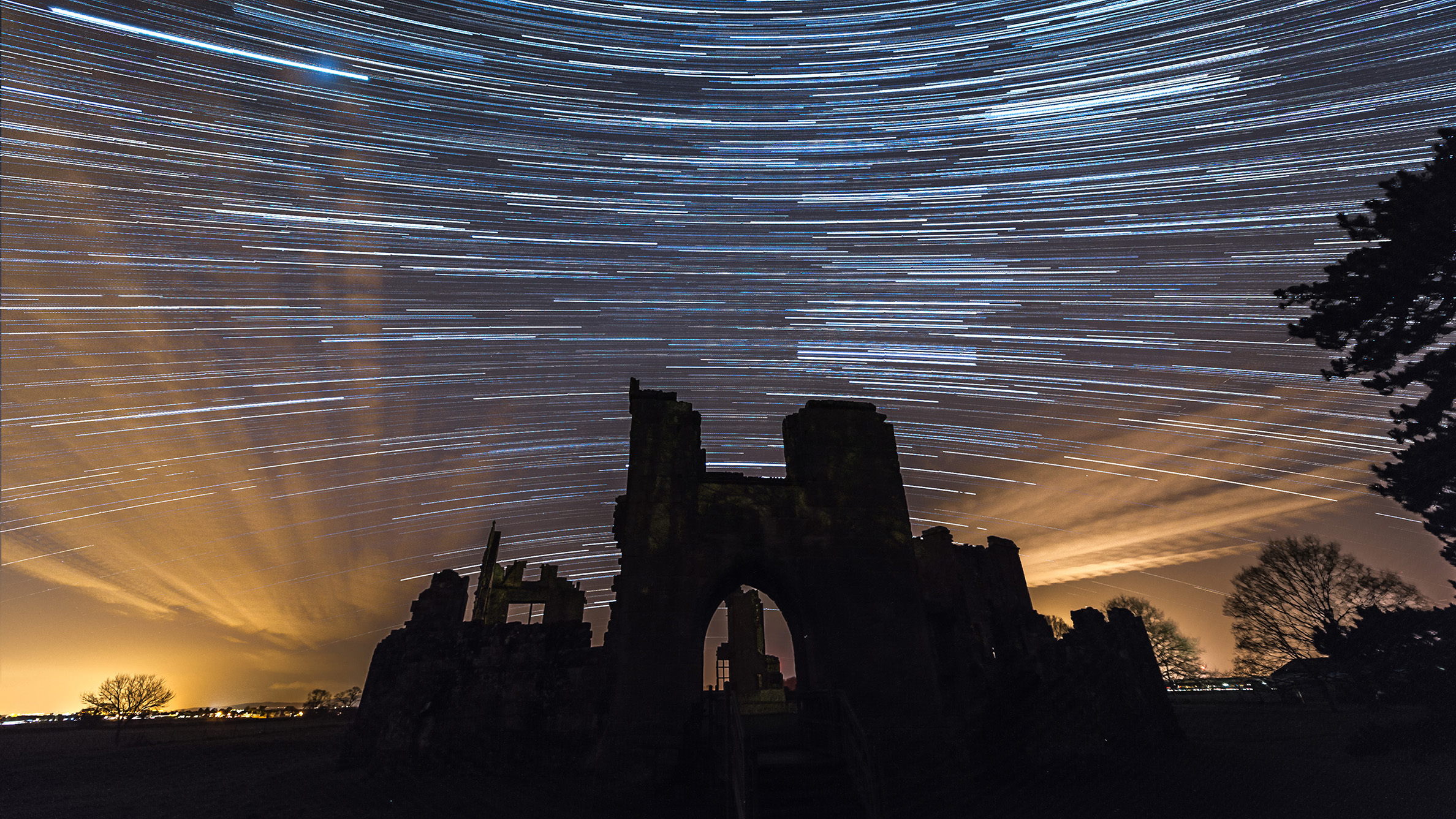 A castle silhouette can be seen in the foreground, while in the background the starry sky is creatively emphasized with a photographic technique