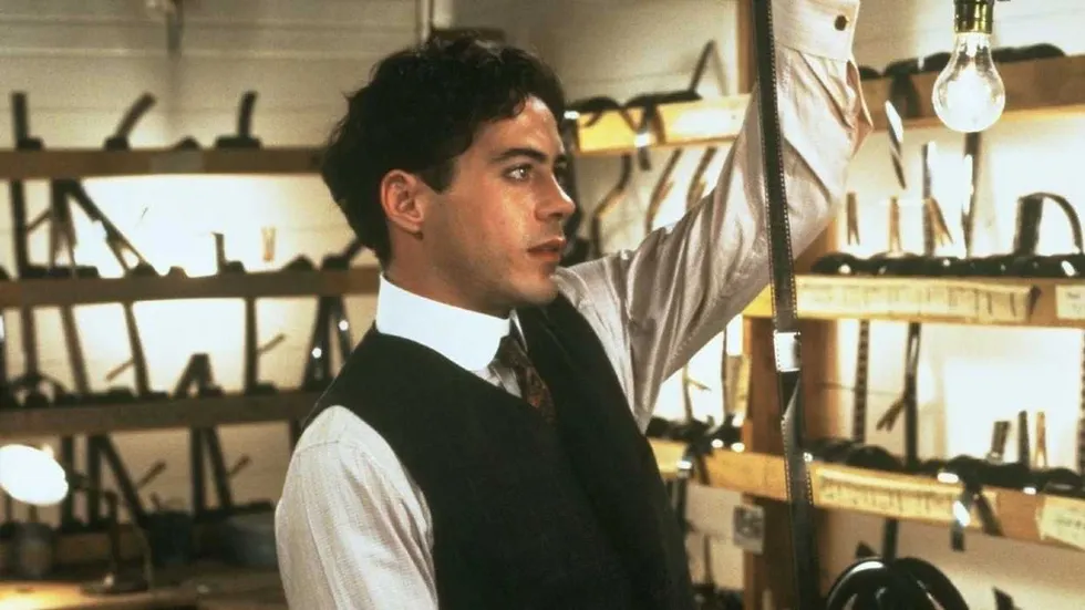 Robert Downey Jr. as Charlie Chaplin holding up a film strip in Chaplin