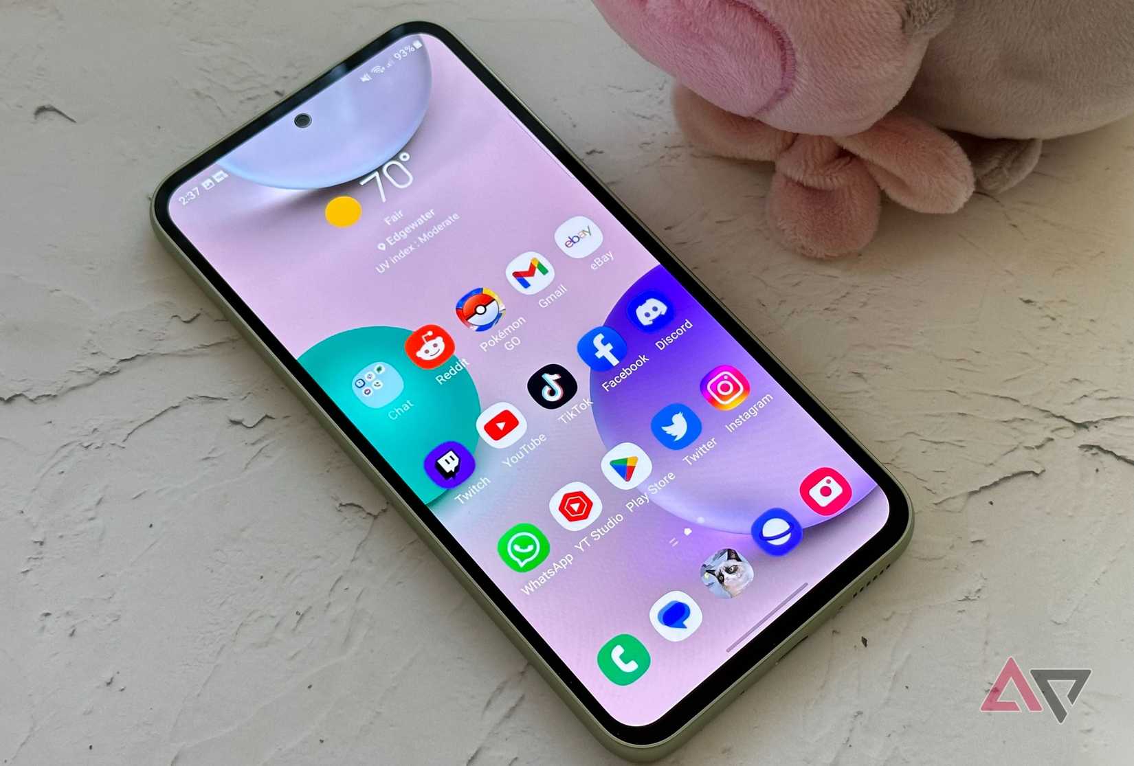 The Samsung Galaxy A54 5G on a table with a plushie next to it