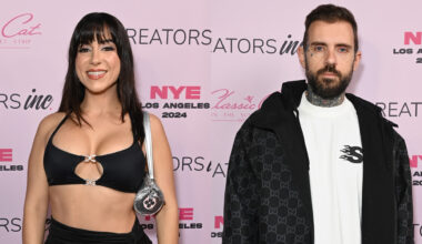 Lena the Plug in a black outfit and Adam22 in a black jacket pose on a pink carpet with backdrop.