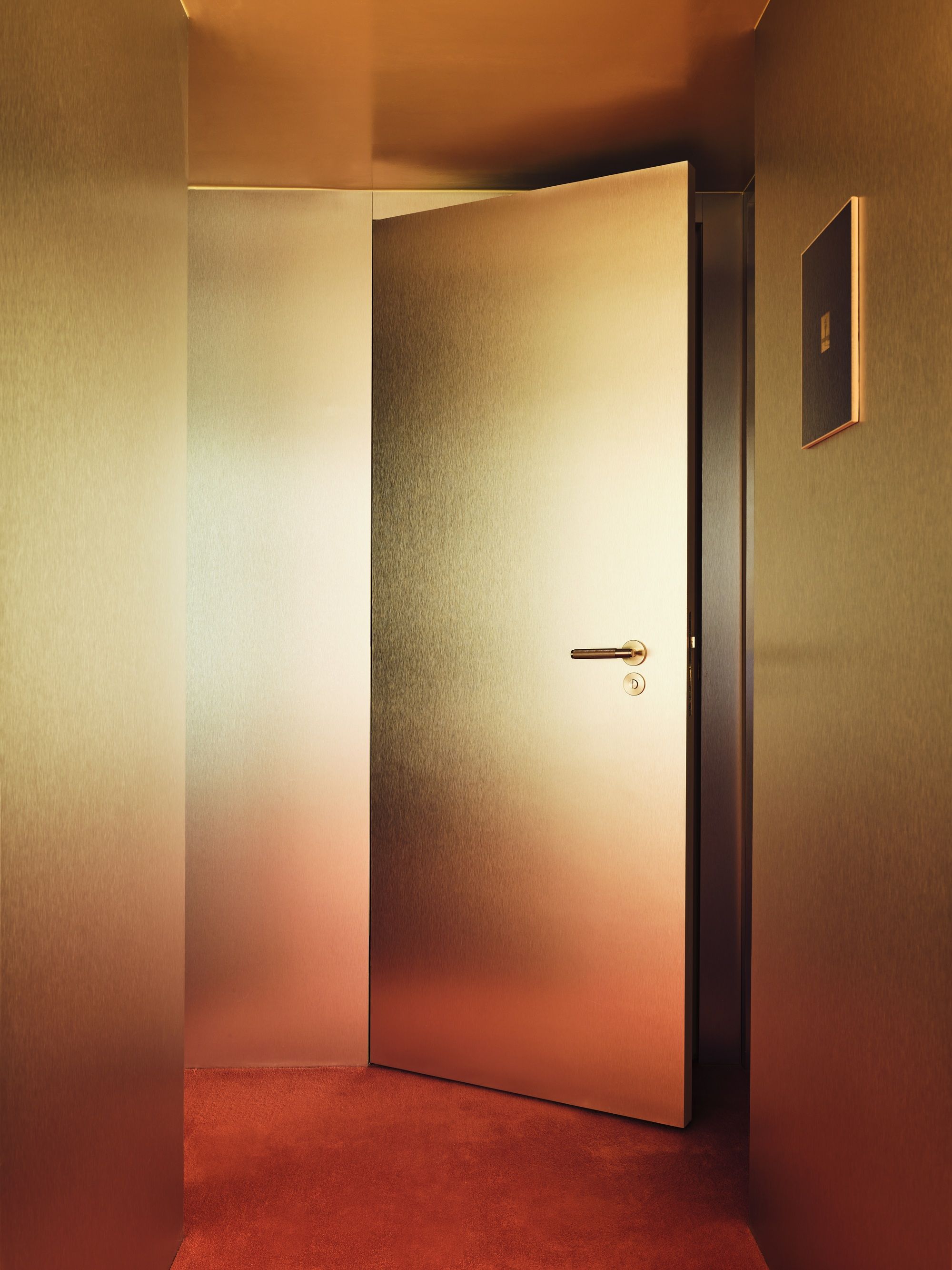 a gold door in a hotel bedroom with a red carpet