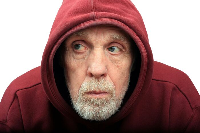 Older man in red hoodie looking away, depicting dementia and mental health challenges