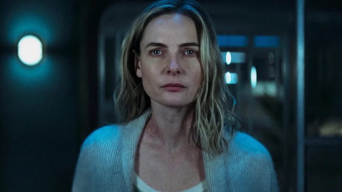 closeup of a blonde woman in white top and blue sweater