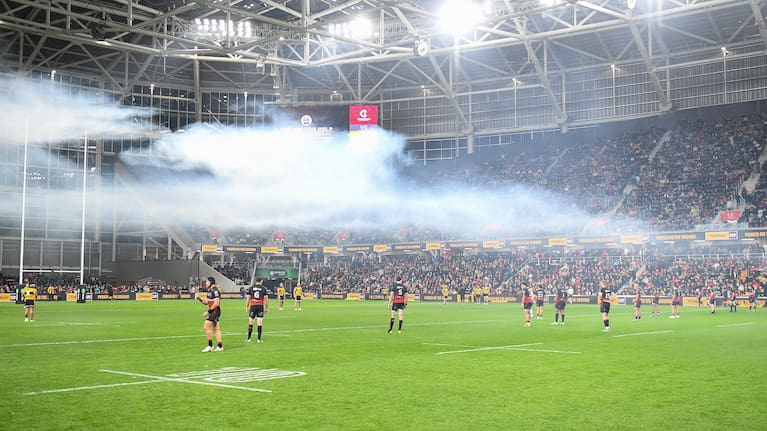 Smoke from fireworks lingers over the Crusaders and Hurricanes players inside Christchurch's new stadium.