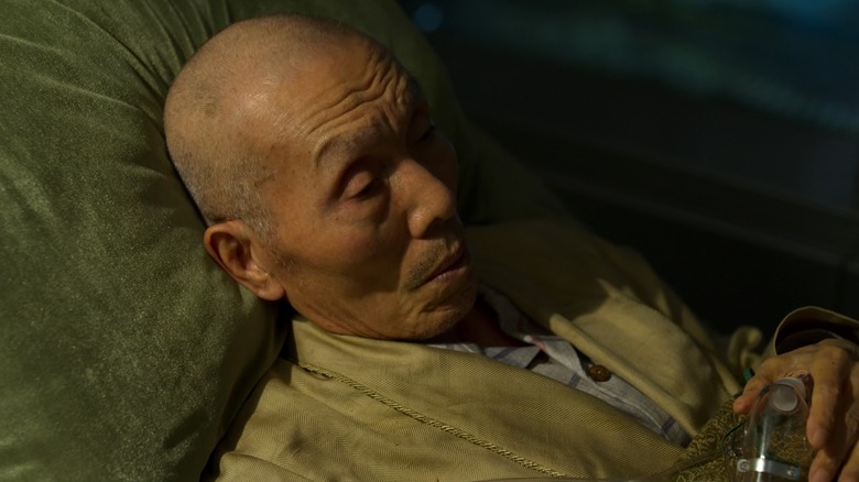 Oh Il-nam laying in bed with oxygen mask in hand