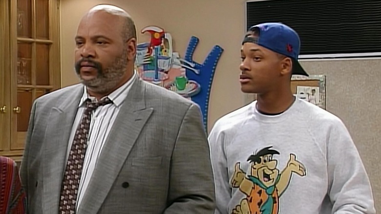 James Avery as Uncle Phil and Will Smith as a fictional version of himself, standing side by side The Fresh Prince of Bel-Air.