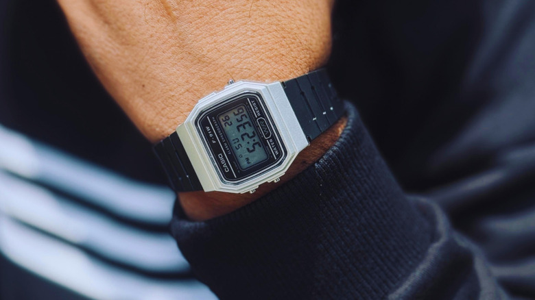A classic Casio digital watch with a silver face and a black band on a person's wrist.