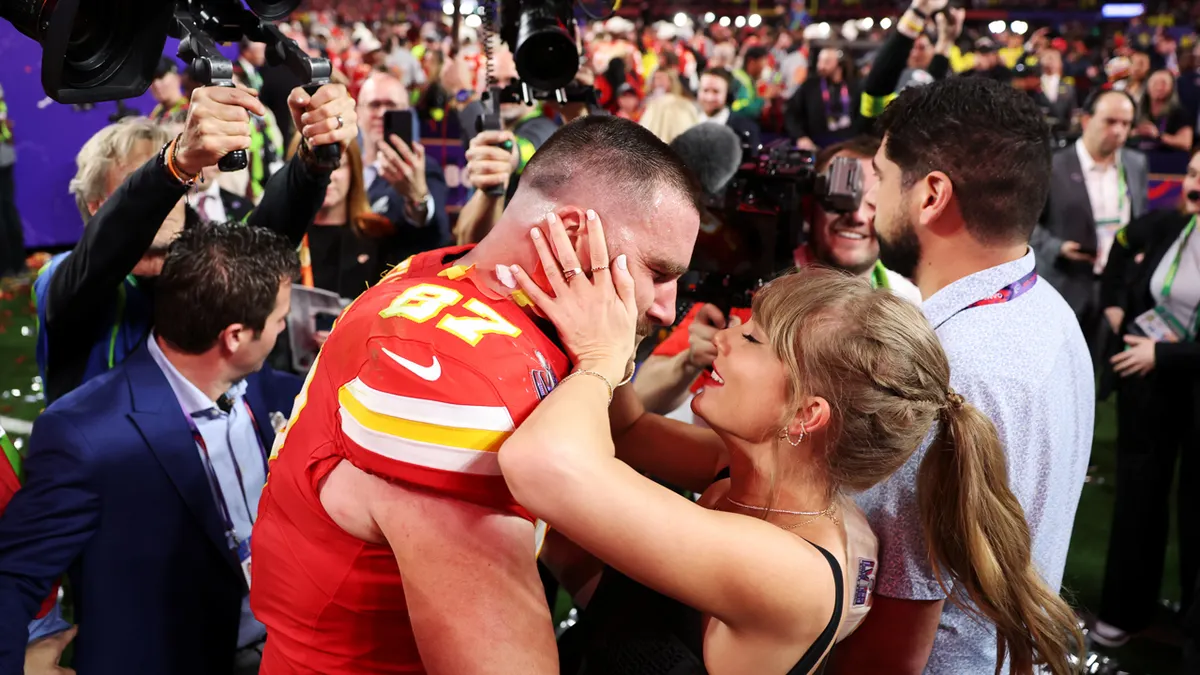 Travis Kelce and Taylor Swift embracing on the field at Allegiant Stadium.