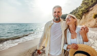 A retired couple walks along the beach.