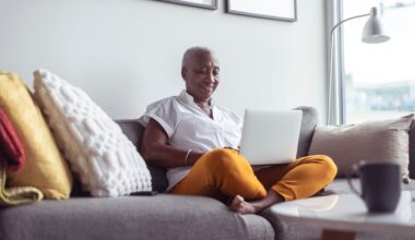 Smiling person using laptop on couch.