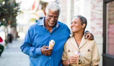 Two people walking down the street, eating ice cream.