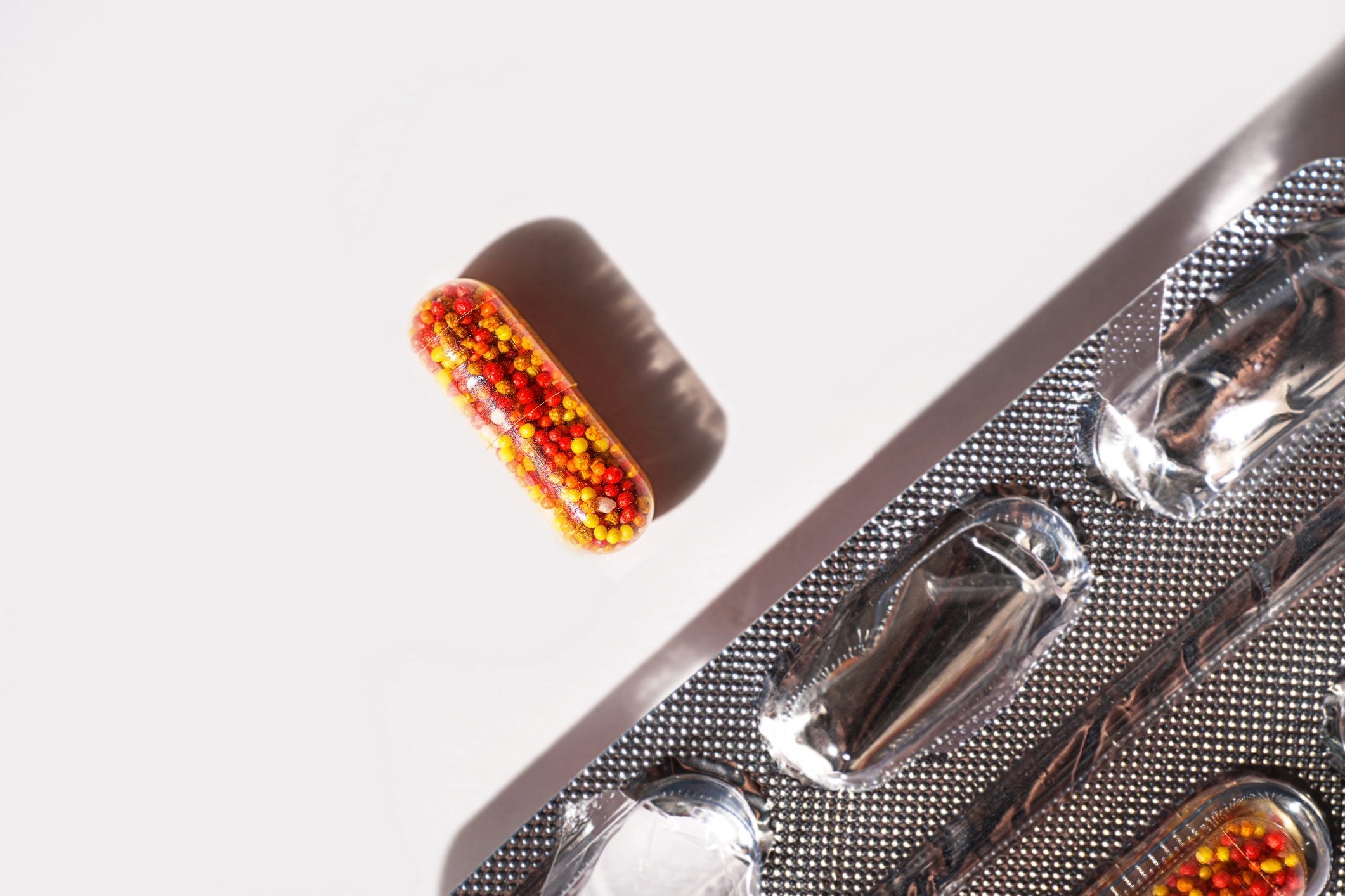 Vitamin pill alongside packet.