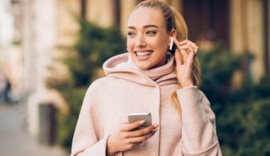 Smiling white woman holding iPhone with Airpods in ear